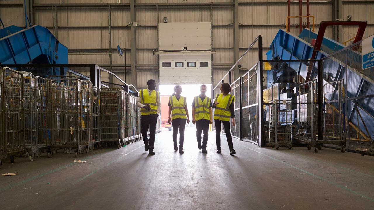 Four employees on the floor of the transferring station reviewing equipment set up