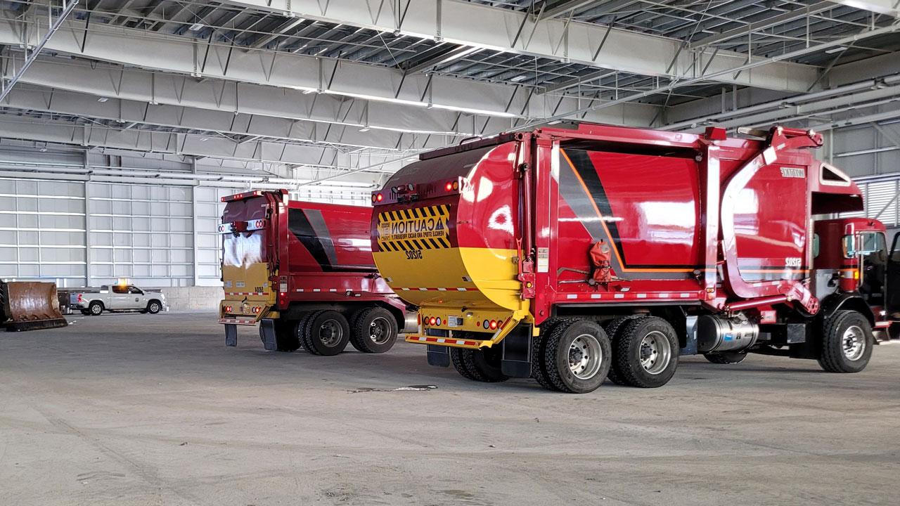 Two garbage trucks inside a transfer station facility