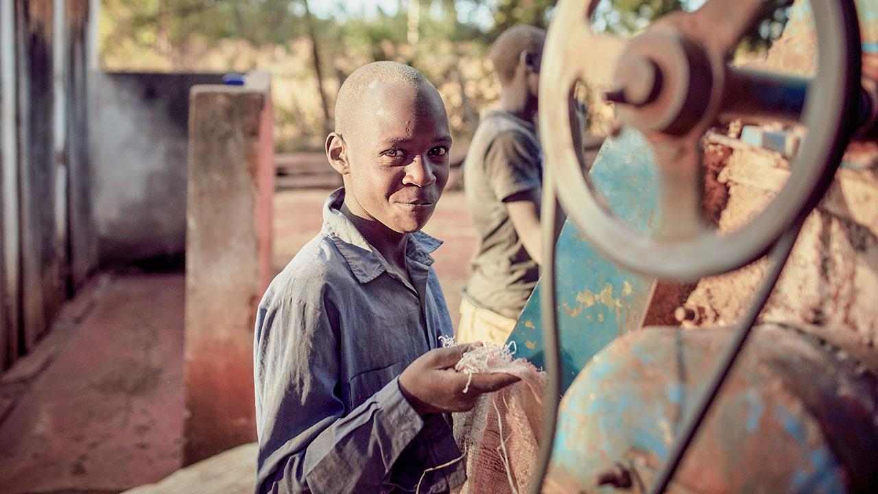 Young man smiles at camera holding grain in his hand